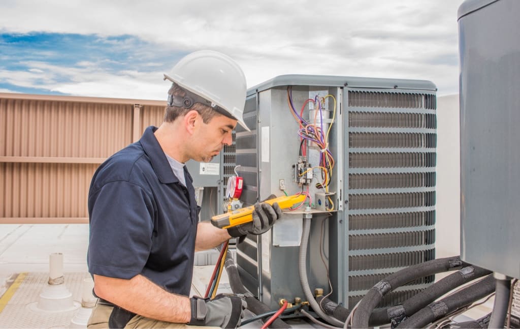 HVAC Technician working on a rooftop HVAC unit in a white hard hat