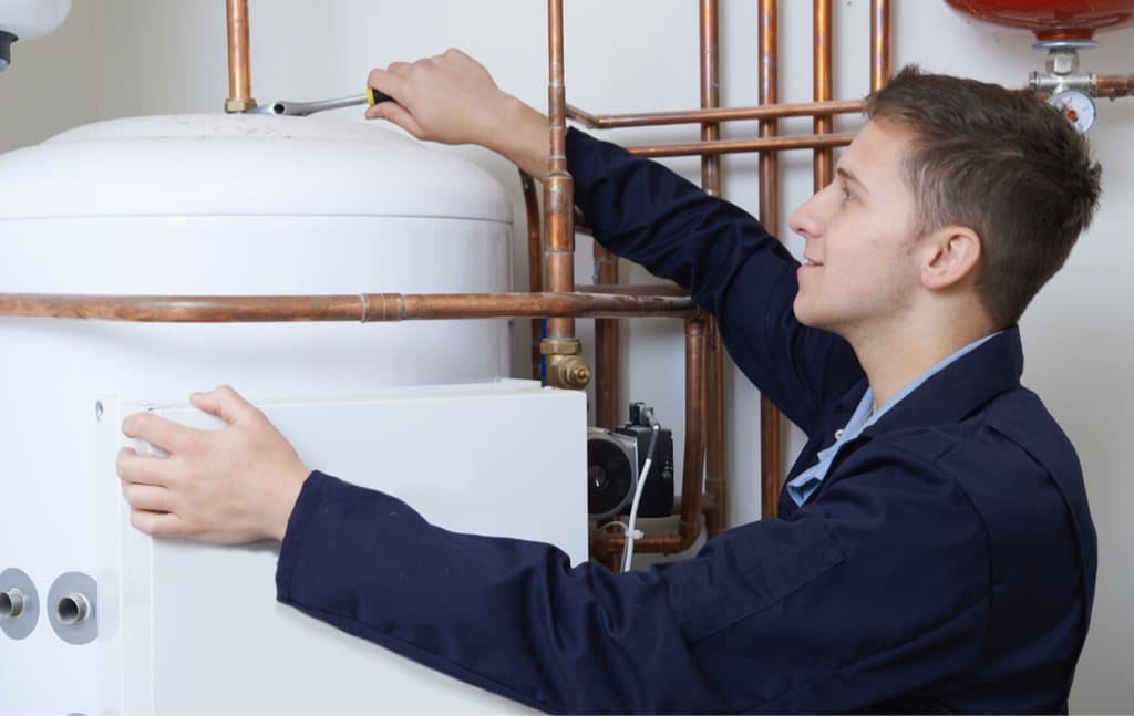 Technial Hot and Cold Technician working on an HVAC Unit in a blue Uniform