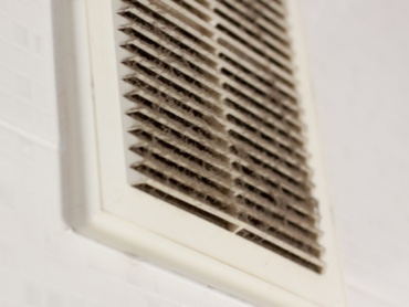 White dirty and dusty air filter cover against a white wall in a residential home