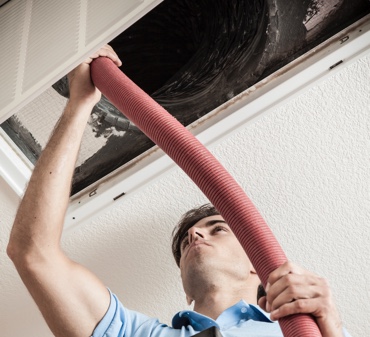 HCAC Tech using equipment to clean an air duct for a residential home