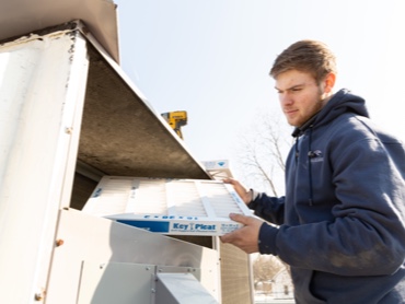 Technical Hot and Cold HVAC Technicions Replacing an Air Filter on an industrial unit outside