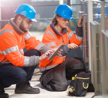 A white man and woman HVAC tech are doing an inspection on a unit