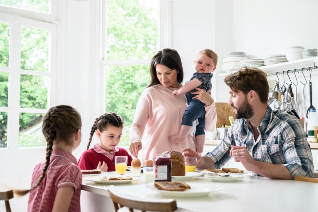 Happy Family of five enjoying breakfast together at the kitchen table