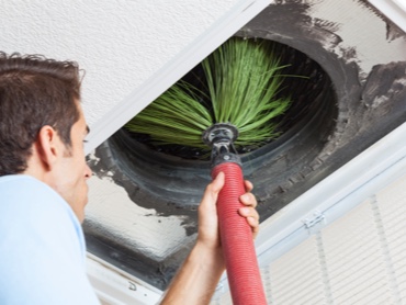 HVAC Technician Cleaning Air Ducts with a Brush