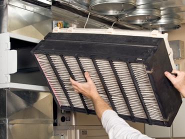 HVAC Technician Installing Air Filter into an Residential Air Conditioning Unit