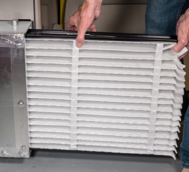 HVAC Technician Installing Air Filter into a Residential Air Conditioning Unit